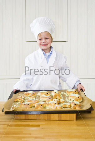 A proudly looking boy, dressed as a chef, showing the easter bunny shaped breads he has baked