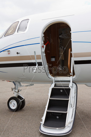 white private jet and open ladder, red carpet at the airport on a background cloudy sky