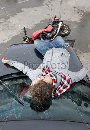 Motorcyclist is being hit by a car, and lies unconsciously on the smashed windscreen, bleeding heavily