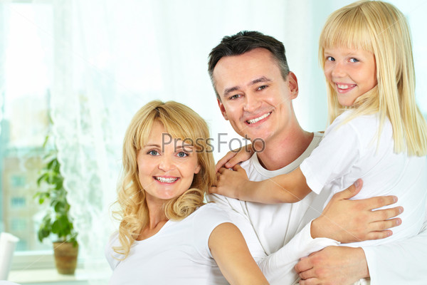 Cheerful family of three smiling at camera, father holding daughter in arms