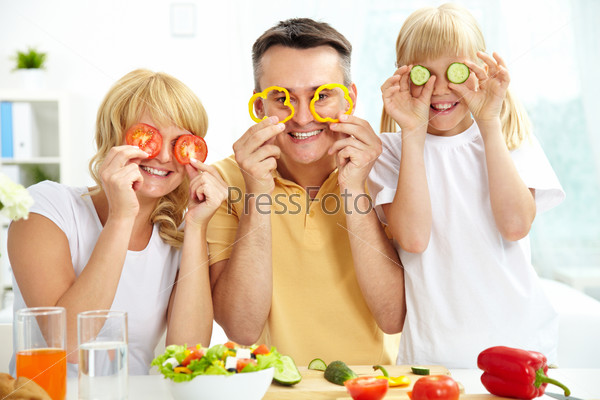 Cheerful family playing with vegetables in kitchen, healthy food