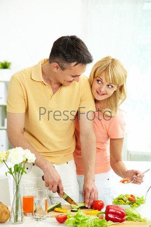 Vertical shot of loving couple cooking healthy food together