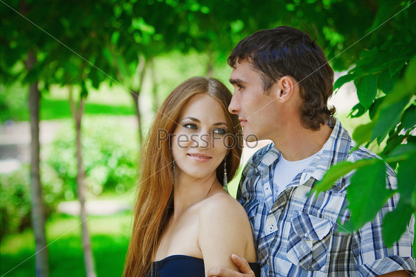 the guy with the girl hugging and kissing in the green foliage of trees