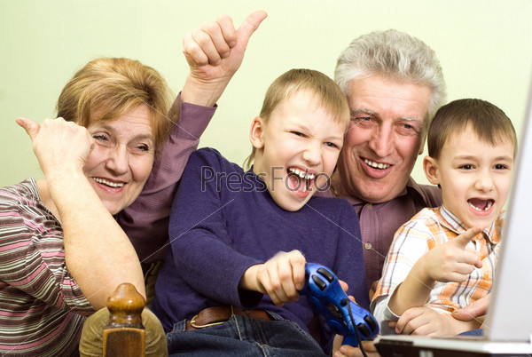 happy grandparents with their grandchildren play on the computer