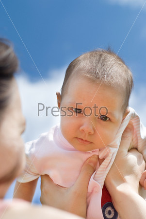 Mother holds baby against the sky