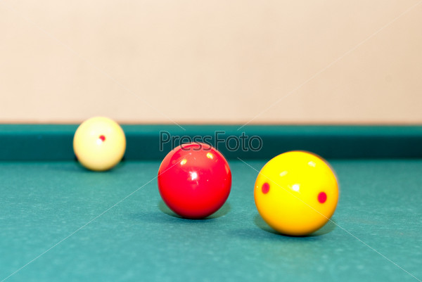 Three billiard balls, used for caroms or carambole on a table, with selective focus on the red ball