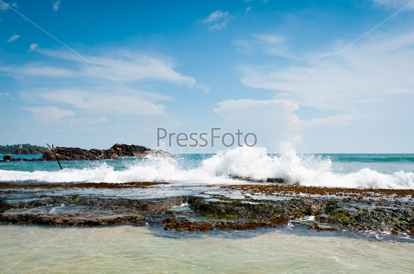 Beautiful stones and coral in the waves under blue sky