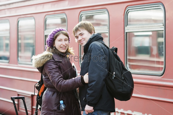 Happy young couple waiting for train on railway station platform