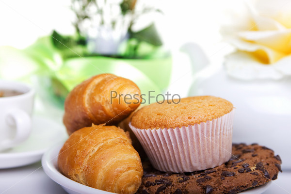 continental breakfast with croissants, cake, chocolate cookies and tea