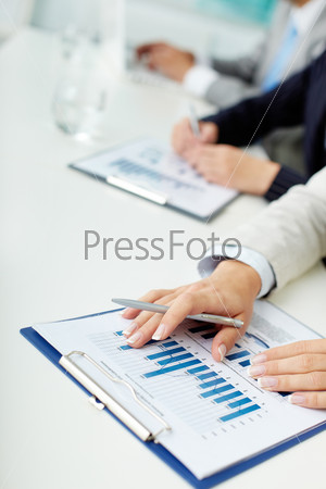 Image of female hands with pen over business document in working environment