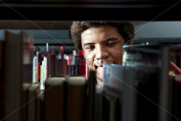 Young man browsing through the racks of books in a library