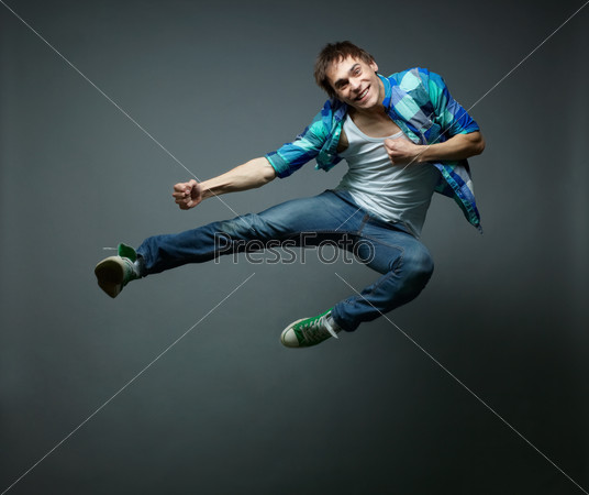 Guy with a wide smile jumping sideward and looking at camera