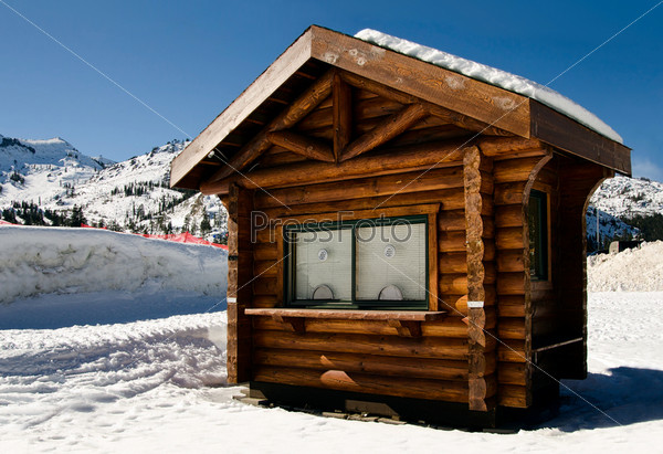 small wooden cabin with two windows in the mountins in the snow