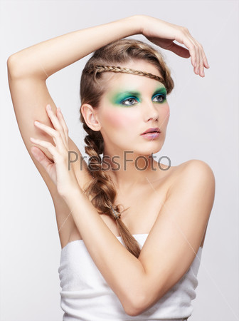portrait of beautiful young dark blonde woman with creative braid coiffure posing on gray