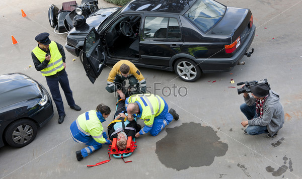Бригада врачей, пожарный и сотрудник полиции помогают жертве автокатастрофы