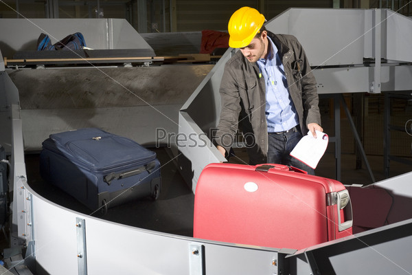 A maintenance engineer inspecting a luggage handling conveyor belt at an airport