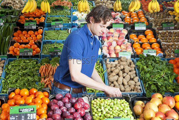Продавец фруктов и овощей в магазине