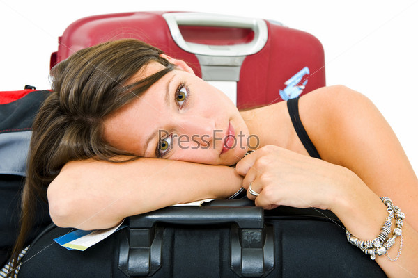 Young woman, resting her head on a suitcase, weary from traveling