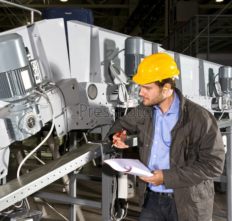A maintenance engineer checking an industrial conveyor belt