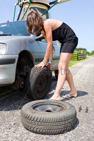 Young woman changing a flat tire