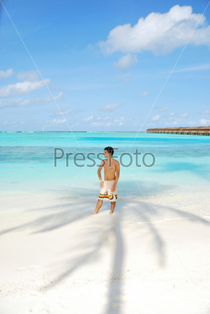 beautiful photo of a young adult standing in the shadow of a palm tree in Maldives