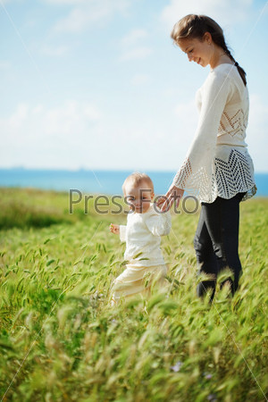 Mother walking with her baby in spring green field