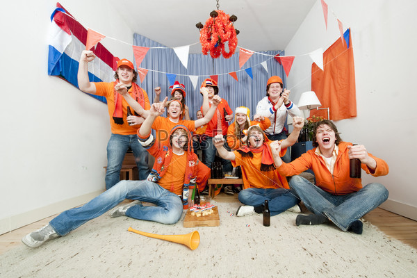 Group of ten cheering sports fans watching their national sports team at home