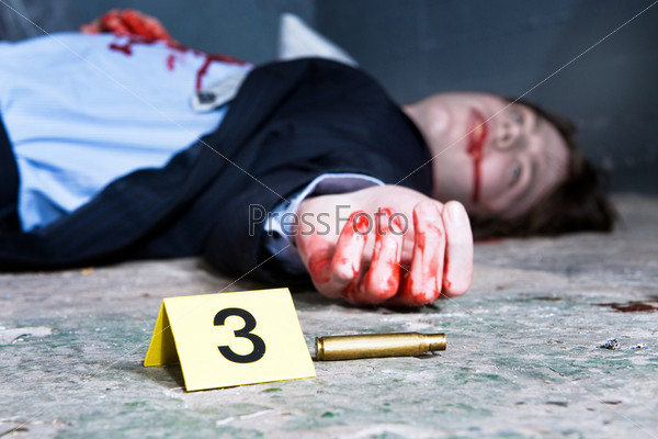 Empty cartridge found on a crime scene with a yellow placard with number three and a dead body in the background