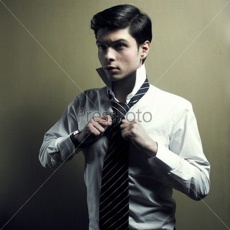 Portrait of a handsome stylish young man tie a tie