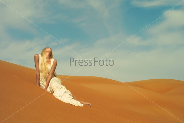 Beautiful blonde in white dress in orange desert. UAE