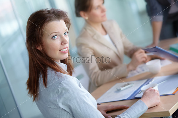Image of pretty female looking at camera in working environment