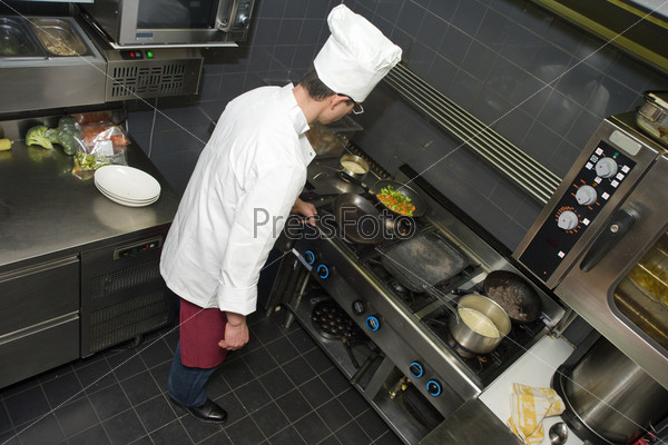 A Chef behind the stove, preparing dinner in a professional kitchen