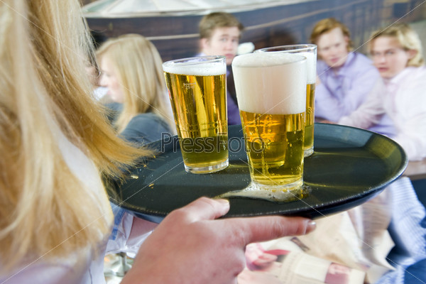Waitress, bringing a round of beers to a waiting group of customers