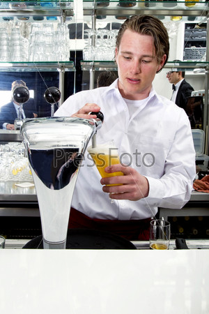 a bartender tapping a beer from his beer pump with customers in the reflection of the mirror