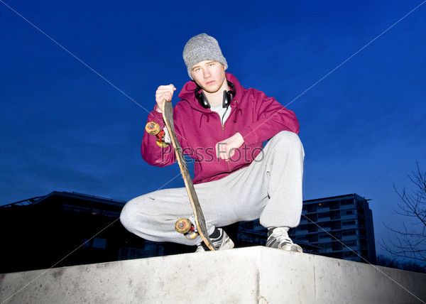 Young skateboarder posing on a concrete ledge