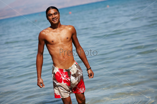 Young man looking at camera while standing in water