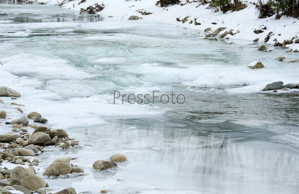 Winter (spring beginning) mountain river view with ice and on water surface