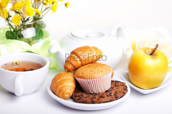 continental breakfast with croissants, cake, chocolate cookies, apple and tea