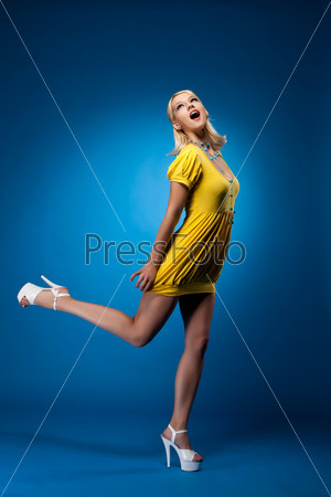 Tall woman in yellow sexy dress jump on blue
