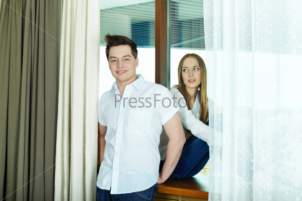 Happy couple in smart casual clothes by the window