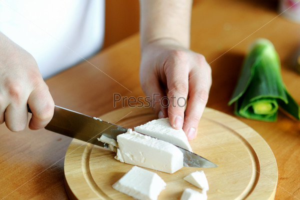 An image of hands cutting cheese on the board, stock photo