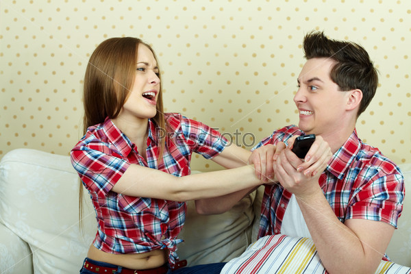 Portrait of young couple fighting beacause of remote control
