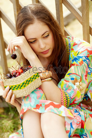 Portrait of pretty girl in country dress holding cherries