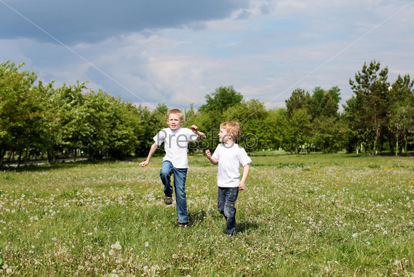 Two twin brothers outdoors on the grass, stock photo