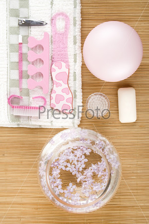 On the wooden table flowers, cream, soap, a brush for cleaning the face and pink pedicure set