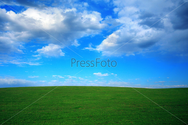 Green field and blue sky with thunder-clouds on it, stock photo