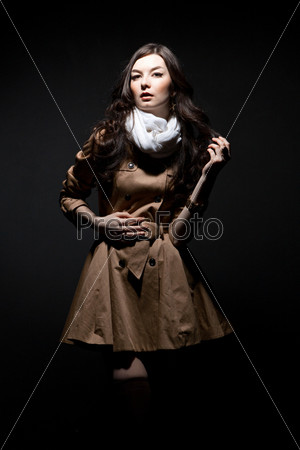Портрет чувственный молодой женщины в коричневом плаще на темном фоне