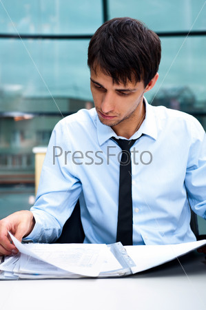 Portrait of a business man working at his office with papers