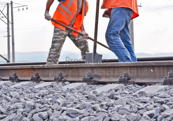 railway embankment, rails and workers in orange vests