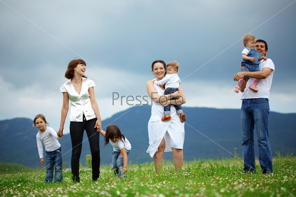 Group of happy parents with children resting in field, stock photo